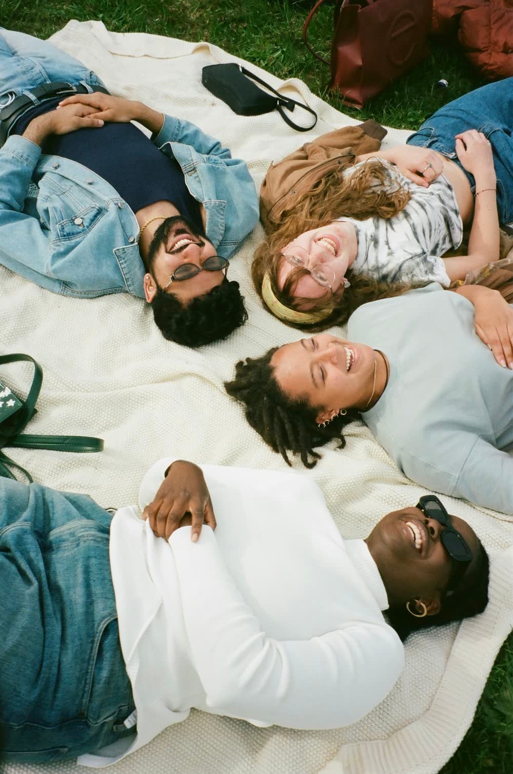 Friends lying together on a blanket, laughing